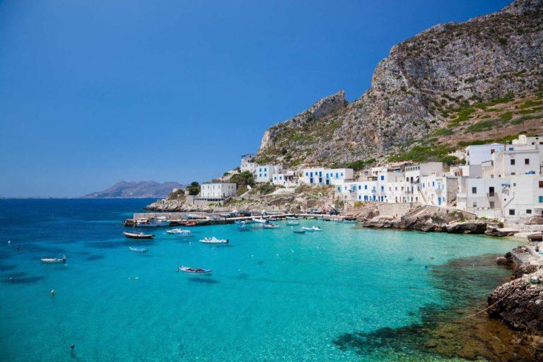 Baia con acqua turchese, barche ormeggiate e case bianche sulla riva a Lipari